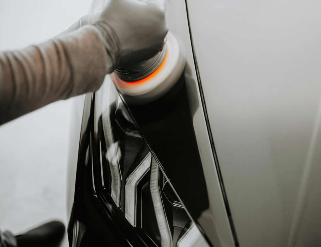 Ruka koja drzi aparat za smirglanje automobila i obradjuje deo iznad farova